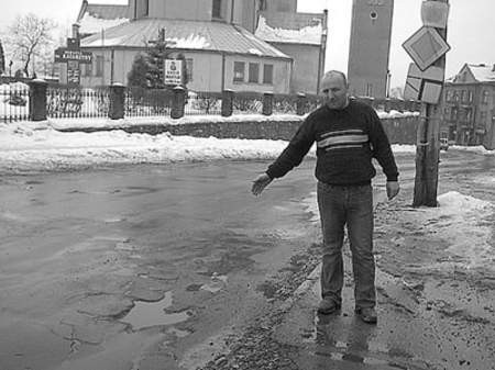 Mirosław Latosiński pokazuje dziury w nawierzchni ulicy Wolności.