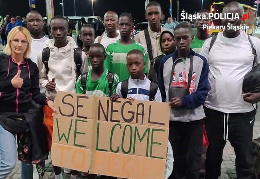 Policjantka wraz z piłkarzami z Senegalu, którzy trzymają w rękach plakat z napisem "Senegal Welcome to Piekary"
