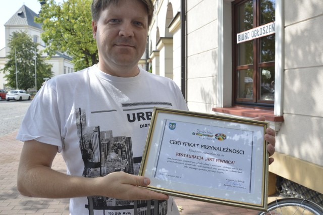 Jacek Rybus prezentuje certyfikat, jaki otrzyma każda z dziesięciu restauracji, które włączyły się w miejską akcję