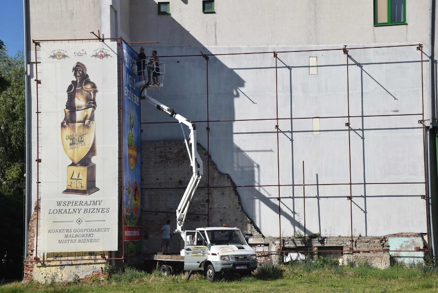 Malbork. Brzydka ściana w centrum miasta została przesłonięta miejskimi reklamami. Już można oglądać efekty