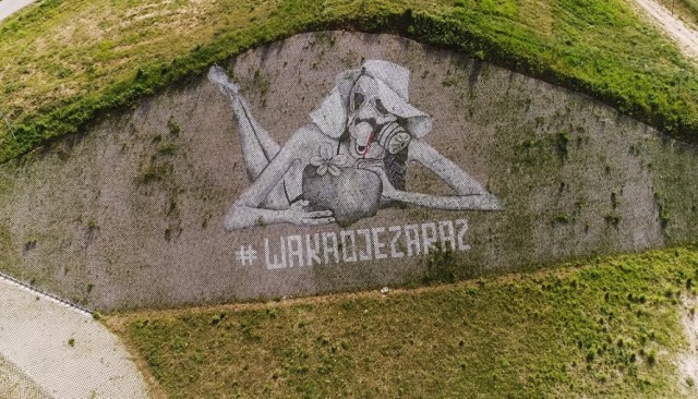 Kobieta w masce gazowej przy S3
Mural przedstawia kobietę w bikini, która znajduje się w pozycji leżącej - poza typowo plażowa. Ma wakacyjny kapelusz, oraz napój, który leniwie za pomocą słomki sączy z naczynia przypominającego owoc palmy kokosowej. Może to nawiązanie do plaży w Martynice, gdzie roślina ta występuje? Interpretacja dowolna. Elementem, jaki jednak świadczy o nowej rzeczywistości, do której byliśmy zmuszeni dość szybko się przyzwyczaić, jest maska gazowa - prawdopodobnie model GP-7. Robi wrażenie prawda?