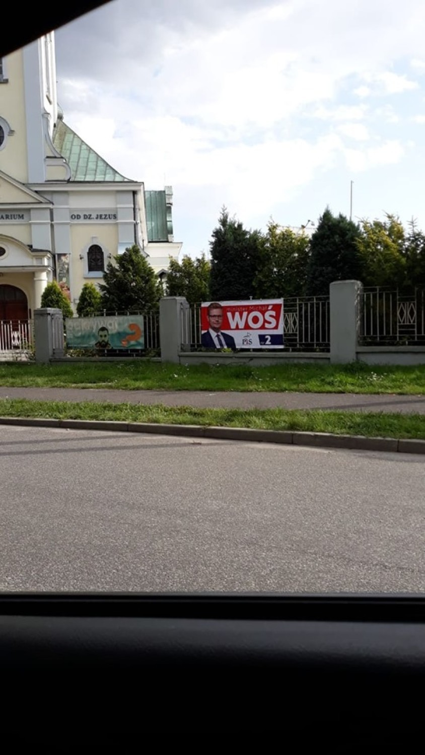 Plakat wyborczy kandydata PiS na płocie parafii w Chwałowicach