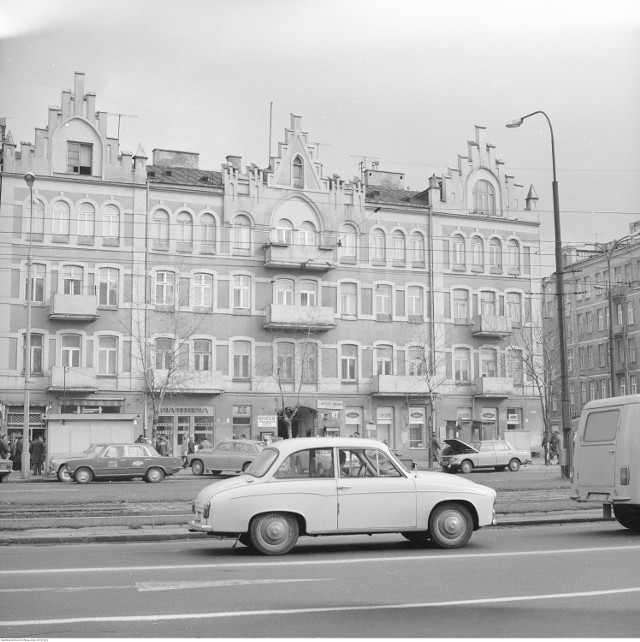 Kamienica przy ul. Targowej 62. Widoczne szyldy sklepów i zakładów usługowych. Na jezdni samochód Syrena 105, na dalszym planie Polski Fiat 125p i Wartburg 353.
Data wydarzenia: 1977