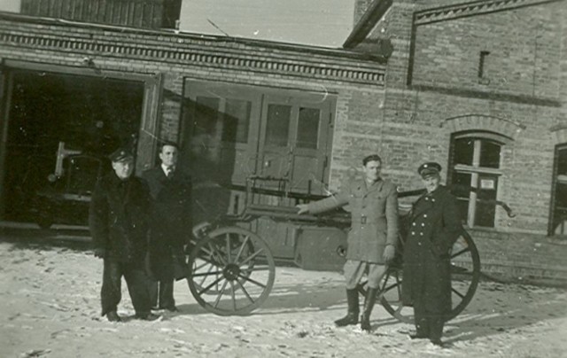 Z prawej w mundurze komendant OSP Goleniów, dh Jan Wróbel, z lewej w mundurze kierowca-mechanik dh Zygmunt Skalik przed remizą OSP Goleniów przy ul. Grunwaldzkiej w Goleniowie, 1948 rok. Pośrodku sikawka konna.