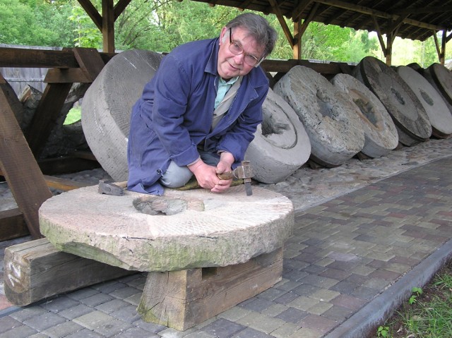 Jan Ekiel demonstruje ostrzenie kamienia młyńskiego. (Archiwum Skansenu Rzeki Pilicy).