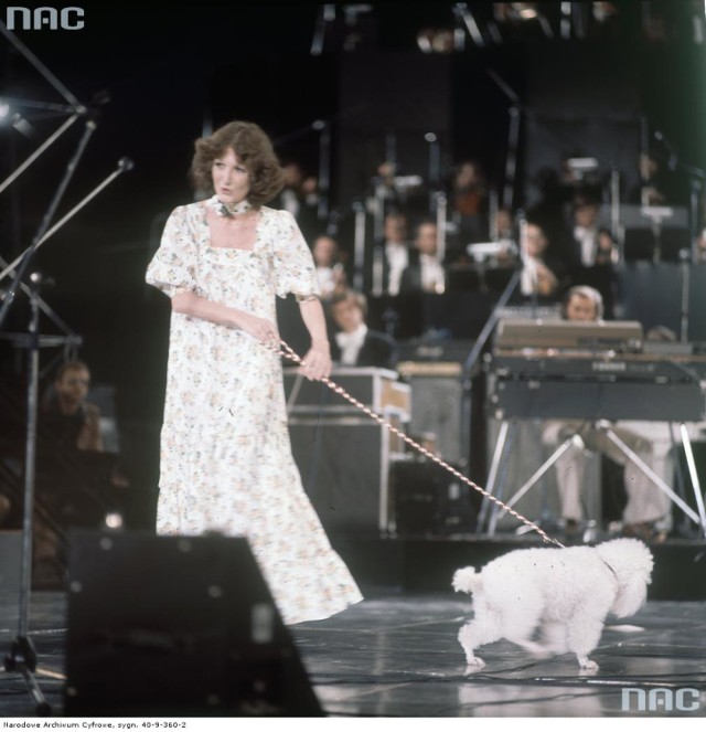Ewa Dębicka z białym pudlem na smyczy podczas występu na scenie.