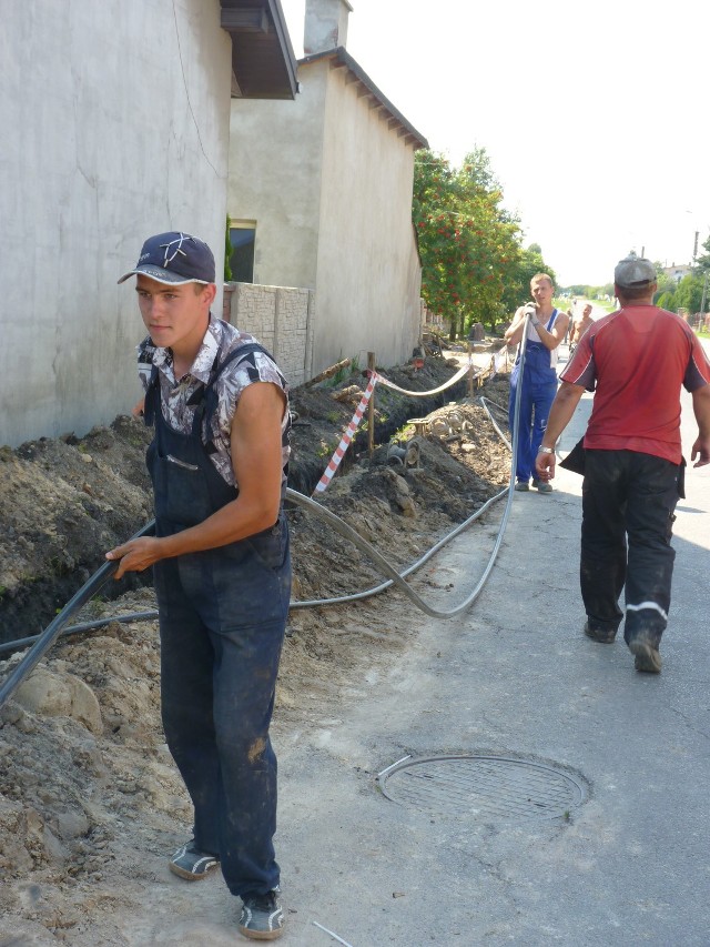 Robotnicy wyciągają i przenoszą stary kabel