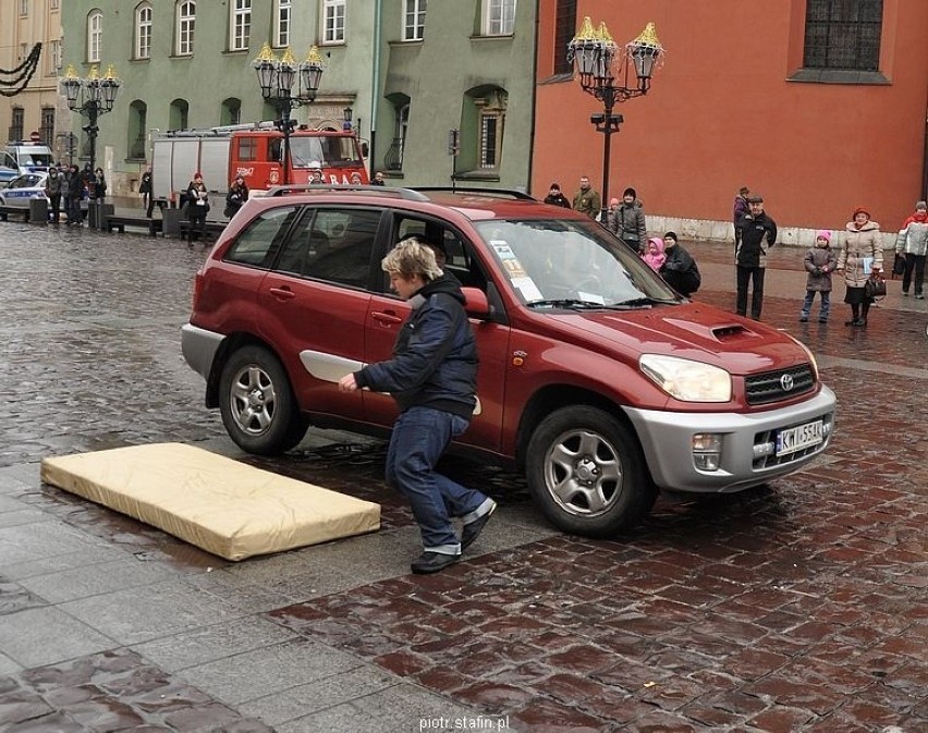 Przejeżdżające auto potrąciło pieszego, który upada na...