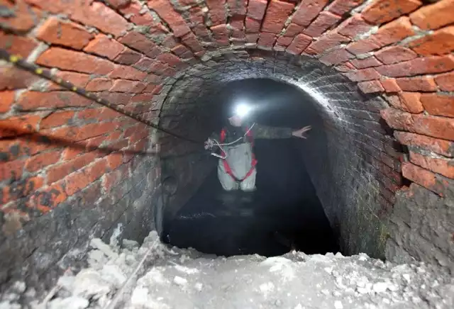 Archeolog Paweł Duma bada zalany wodą tunel
