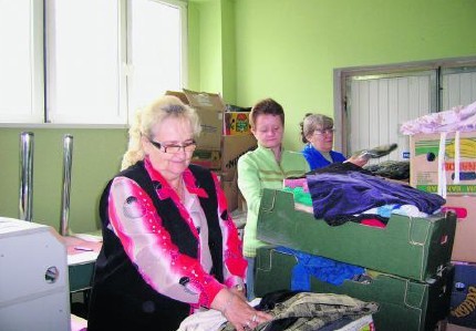 Danuta Lech wspólnie z wolontariuszkami segregują ubrania i środki czystości.