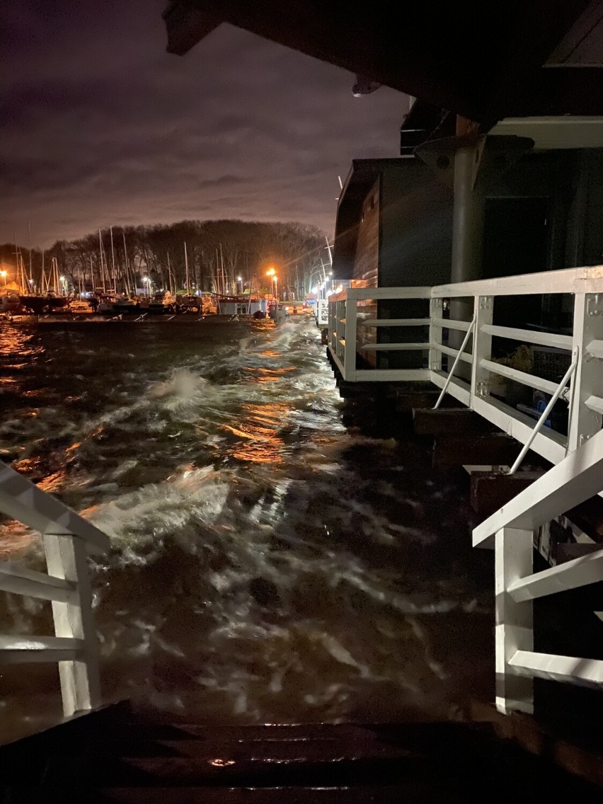 Puck po wichurze. Zatoka Pucka zalewa port jachtowy, podniszczyła pomost, zerwane dachy w blokach, drzewa i gałęzie na ziemi | ZDJĘCIA