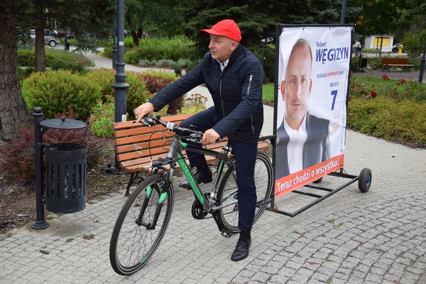 Robert Węgrzyn ciągnie na rowerze przyczepkę ze swoim banerem wyborczym. Chce tak zjeździć całą Opolszczyznę