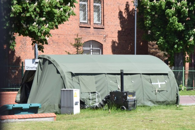 Przed wejściem na teren jednostki wojskowej stoją namioty, w których odbywa się mierzenia temperatury ciała i dezynfekcja rąk.