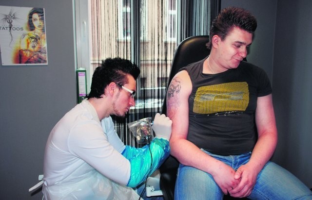Anatol Krygowski w czasie pracy w swoim studiu. Robi tatuaż. Klient będzie miał na przedramieniu robota