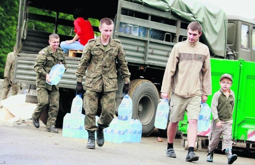 Żołnierze rozpakowują dary i dostarczają je ludziom
