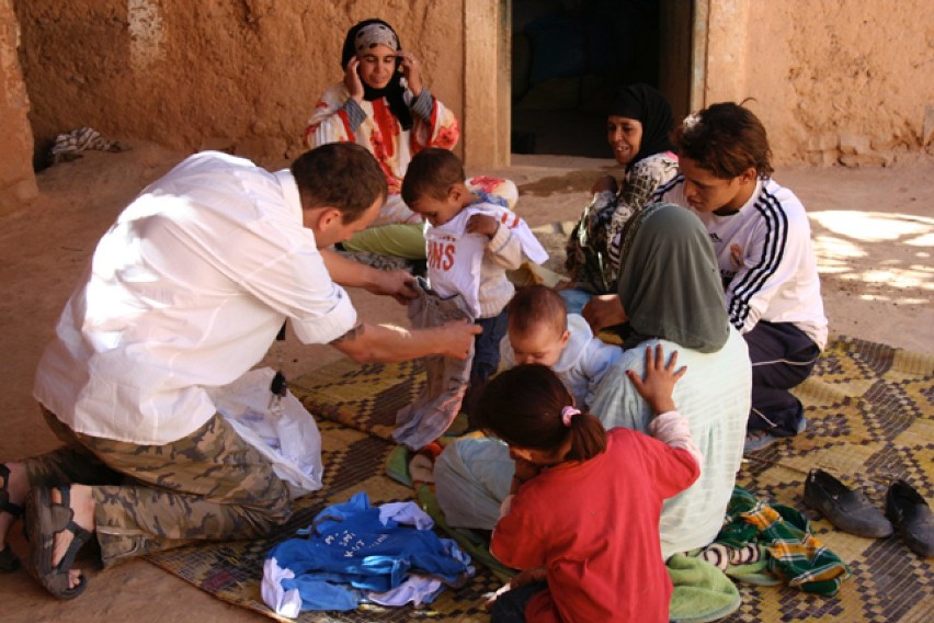 Marokańskie dzieci przymierzają ubranka, które podaje Piotr...