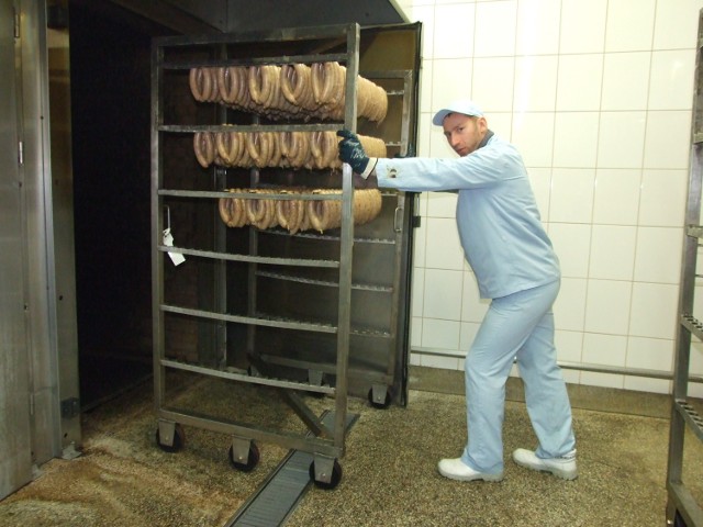 Zakłady Mięsne Szubryt w Chełmcu.  Marcin Borkowski ładuje do komory kiełbasę wiejską. Będzie wędzona w dymie, w niezbyt wysokiej temperaturze . Ogień pali się w piecu po drugiej stronie komory