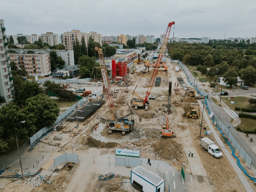 Widok z lotu ptaka na osiedle, otaczające budowę budynki.