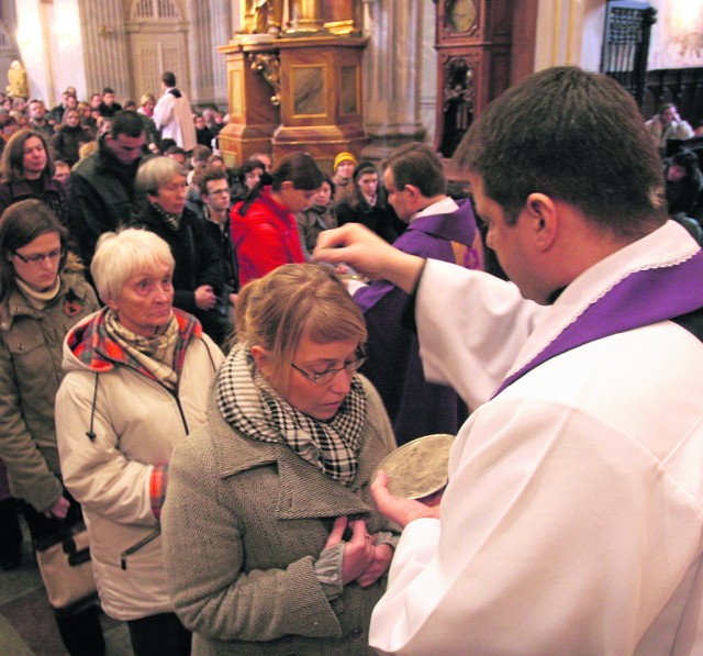 Księża posypują głowy wiernych popiołem