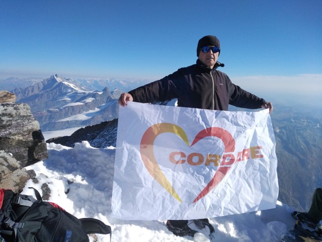 Andrzej Franczyk na szczycie Dufourspitze w Alpach z wniesioną przez siebie flagą fundacji Cordare