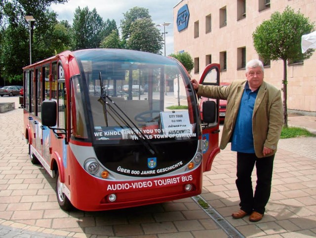 Janusz Gajdzicki obok swojego turystycznego busa przed dworcem PKP w Oświęcimiu.  Stąd przewozi turystów do Starego Miasta i Państwowego Muzeum Auschwitz-Birkenau