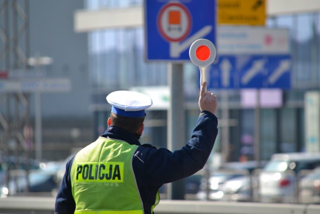 Policjant ruchu drogowego trzyma w ręku tarczę do zatrzymywania pojazdów